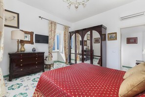 Une chambre à coucher avec un lit, une commode, un miroir et des œuvres d’art accrochées aux murs.