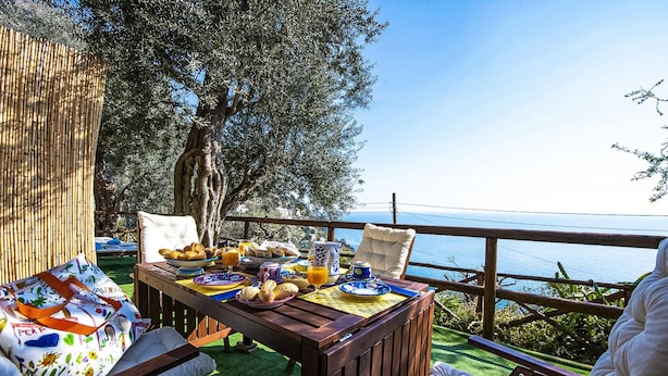 An outdoor dining area with a table set for breakfast, overlooking a body of water. - Maison Don Rafe in Positano (Positano)