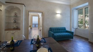 Un vaste espace de vie comprenant une table à manger dressée pour le repas, un canapé de couleur turquoise et une vue sur la mer par une grande fenêtre.