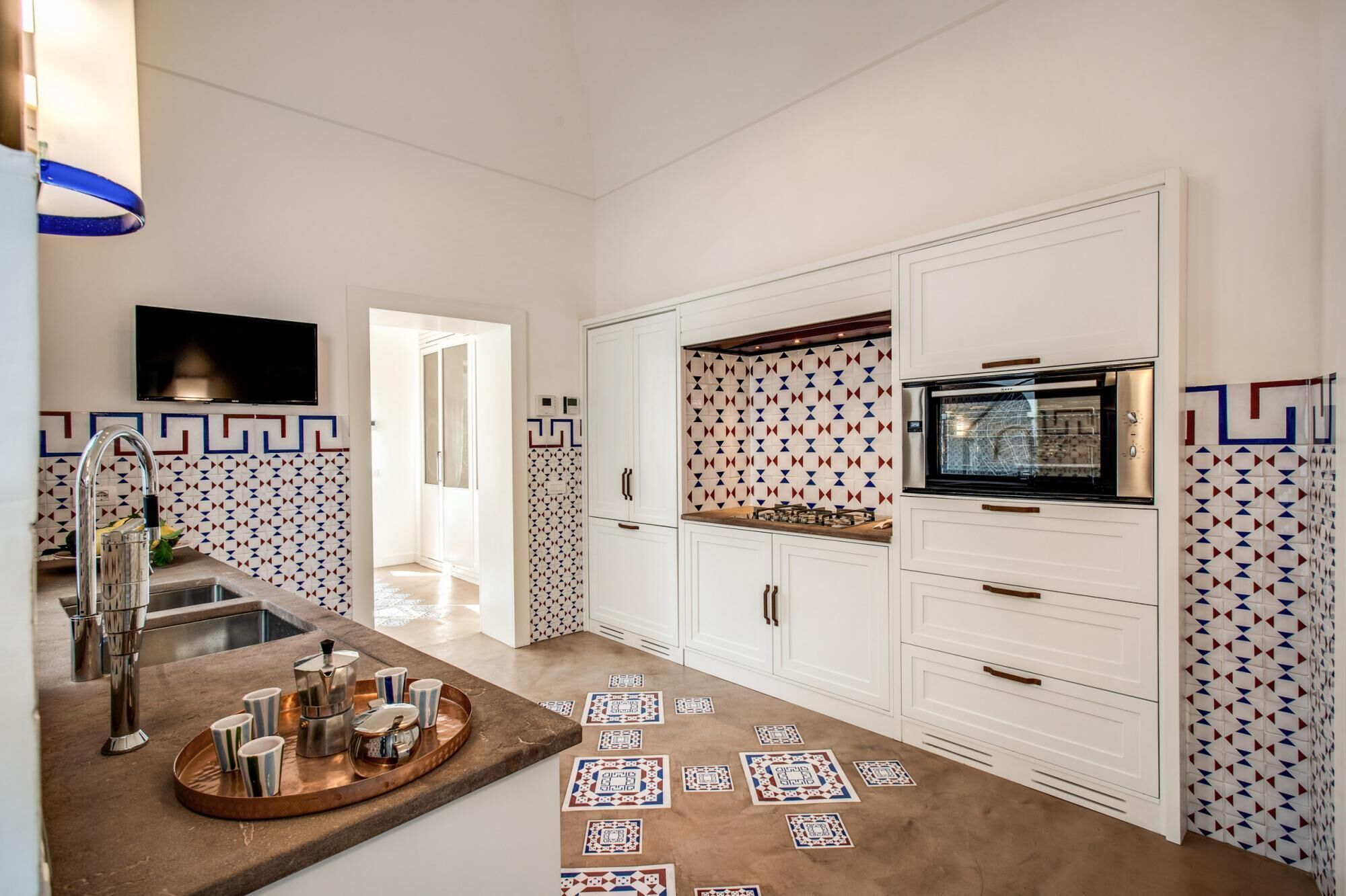 Una cocina moderna con armarios blancos, horno empotrado y salpicadero de azulejos.
