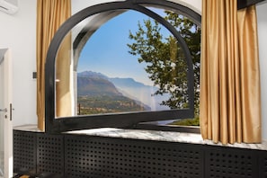 Ein Zimmer mit einem großen Bogenfenster und Blick auf die Berge.