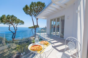 Un balcon avec une table dressée pour deux personnes, offrant une vue imprenable sur l’océan.