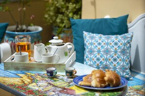 A breakfast setup with a teapot, cups, and pastries on a table with a colorful tablecloth. - Amore Rentals - Casa Barbera B (Positano)