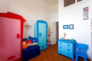 A child's bedroom with a pink wardrobe, a blue dresser, and a blue chair.