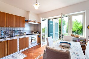 Eine moderne Küche mit Holzschränken, einer gefliesten Rückwand und einem großen Fenster zum Garten hin.