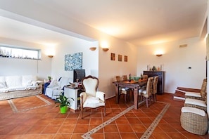 Un grand espace de vie comprenant un canapé, une table à manger et des chaises, un téléviseur et une plante en pot.