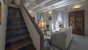 Un escalier menant à un espace de vie avec vue sur la mer, une table à manger et un buffet aux portes vitrées.