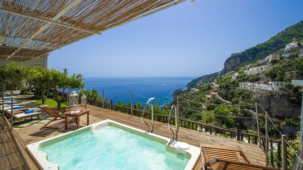 Une piscine sur le toit offrant une vue sur la mer et un paysage montagneux.