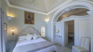 Une chambre d’hôtel classique, dotée d’un grand lit, d’une table de chevet, d’un miroir et d’une porte donnant accès à la salle de bain.