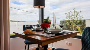 A dining table with a vase of red flowers, two candles, and wine glasses on a balcony with a view of the countryside. - Tradicampo-Cycas-Casa da Cisterna- Romantic little corner - NEW LISTING (Algarvia)
