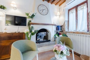 A living room with a fireplace, two armchairs, a television, and a bookshelf. - Rio Delle Fate in Vorno (Capannori)