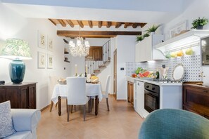 Una cocina moderna con armarios blancos, un comedor con candelabro y una escalera que sube a un nivel superior.