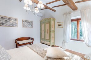 Une chambre à coucher avec un lit, une chaise en bois, une armoire verte et une fenêtre avec des rideaux.
