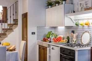 Una cuina amb salabost, un taulell ple de fruita i verdura, una placa de cocció i un rentaplat.