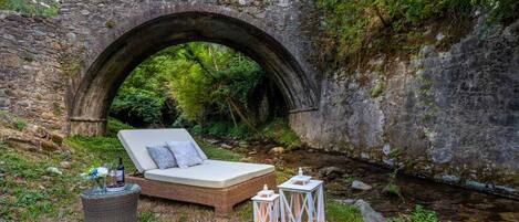 A stone bridge with a bed and lanterns in a forested area.