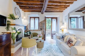 A cozy living room with a fireplace, a sofa, a green chair, and a coffee table. - Rio Delle Fate in Vorno (Capannori)