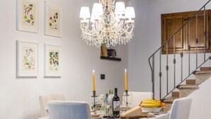 Comedor con candelabro, impresiones botánicas enmarcadas y una mesa dispuesta con velas, vino y fruta.