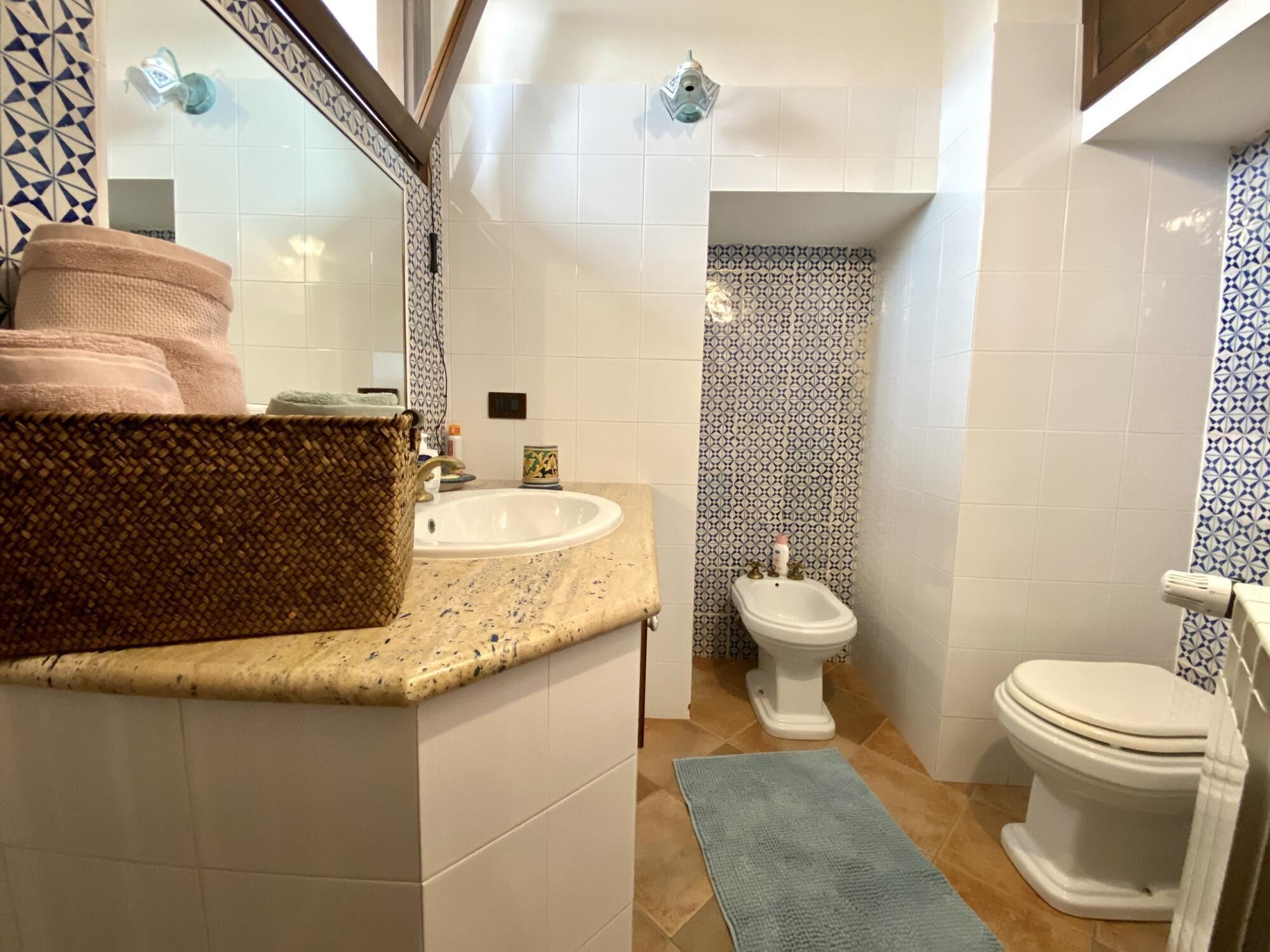 Une salle de bain avec un lavabo, un bidet, des toilettes et une serviette bleue sur le sol.