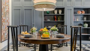 A dining area with a round table, chairs, and a decorative ceiling light. - Gimber Tales a First Floor Apartment (Lucca)