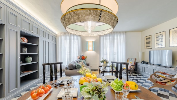 A dining area with a wooden table set for a meal, surrounded by grey cabinets and a chandelier. - Gimber Tales a First Floor Apartment (Lucca)