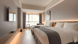 A modern hotel room with a large bed, bedside tables, a flat-screen TV, and a view of the city. -  Grand Banyan Hotel  (Tainan)