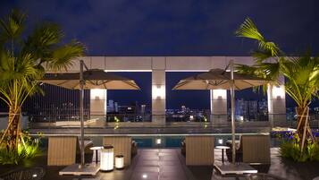 Een buitenzwembad, ligstoelen bij het zwembad