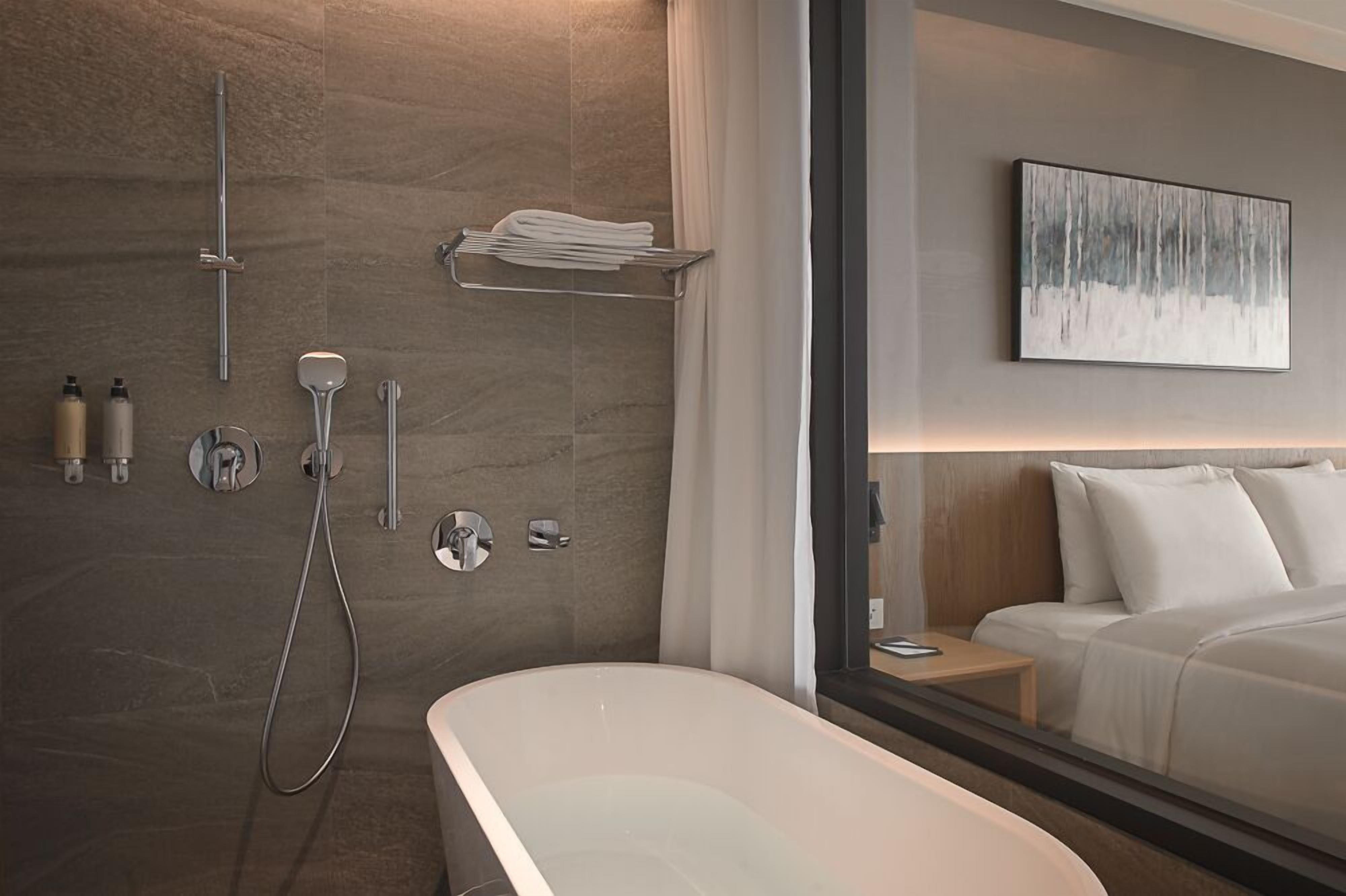 A modern bathroom with a freestanding bathtub, a shower with a handheld showerhead, and a towel rack.
