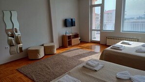 Een moderne hotelkamer met twee bedden, een grote spiegel, een televisie en een houten vloer.