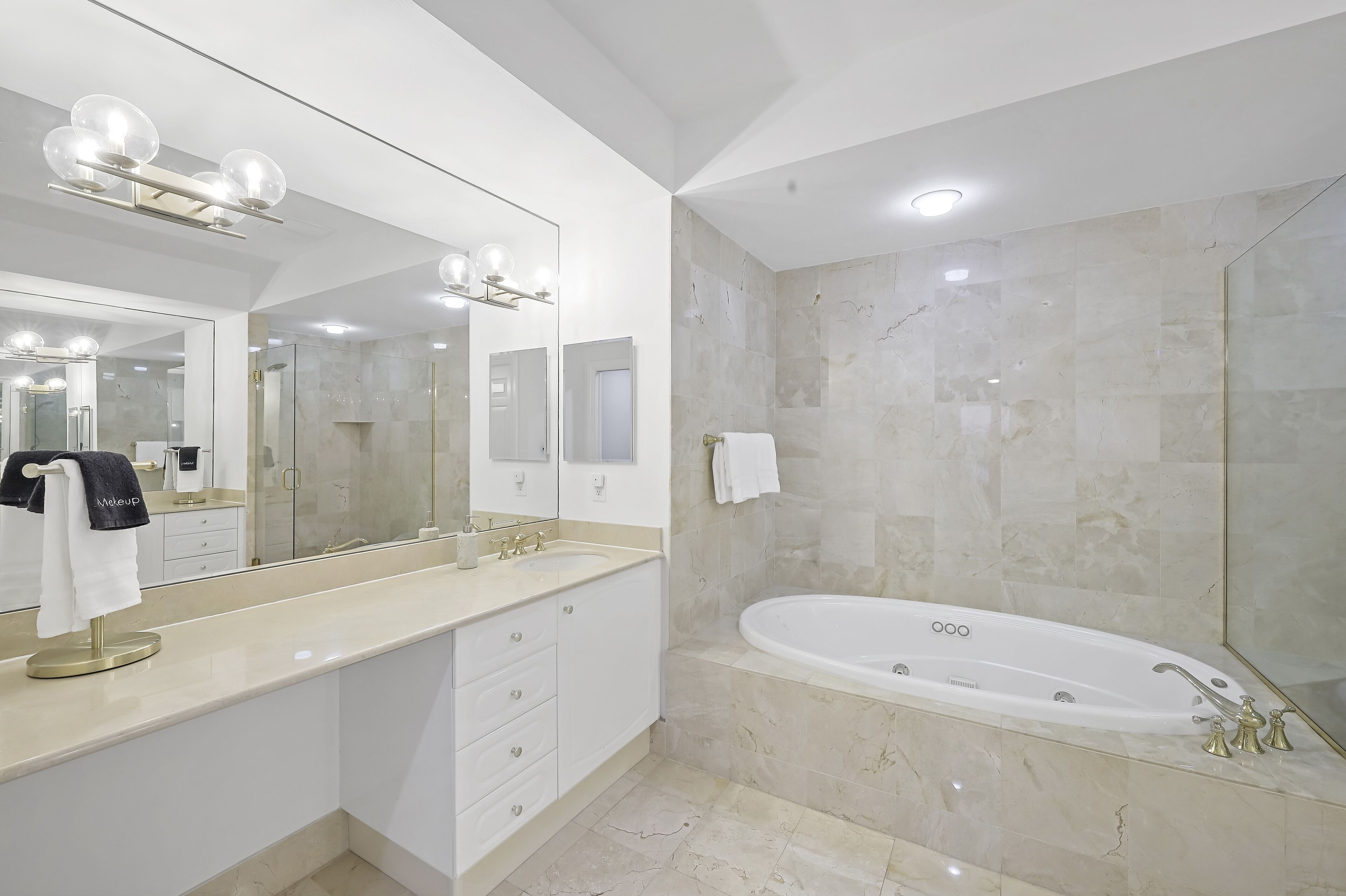 Un baño moderno con un espejo grande, una bañera y un tocador con un perchero para toallas.