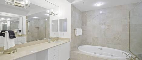 A modern bathroom with a large mirror, a bathtub, and a vanity with a towel rack.