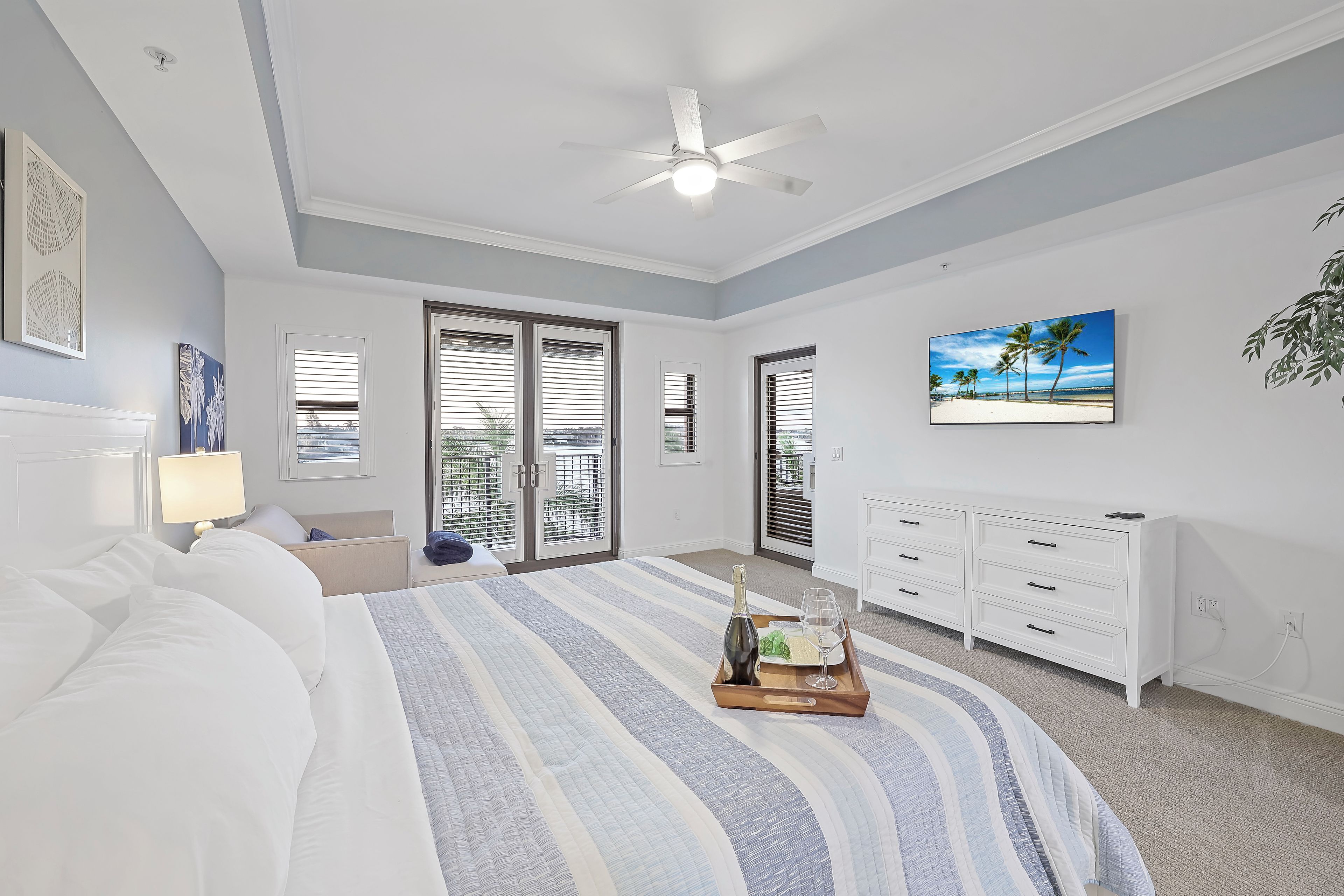 A bedroom with a bed, a nightstand, a dresser, a ceiling fan, and a window with blinds.
