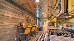 A kitchen with wooden walls, a bar area with stools, a gas stove, and a checkered floor.
