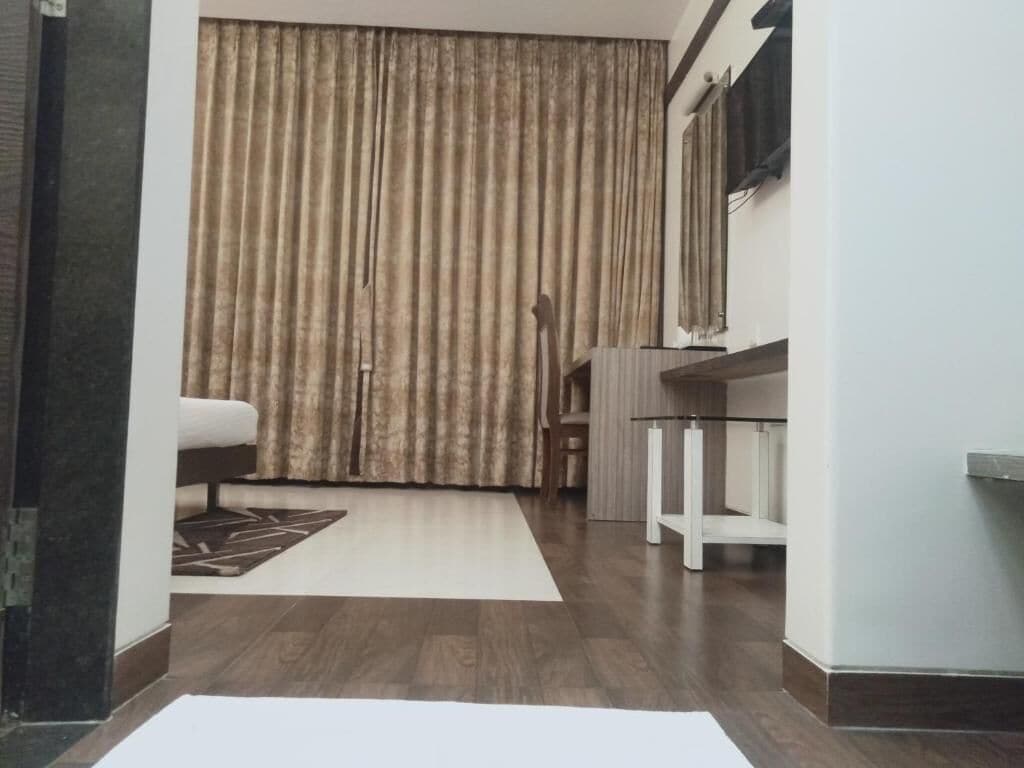 Una habitación con un ventanal grande, una silla blanca, una mesita pequeña y un tapete estampado.