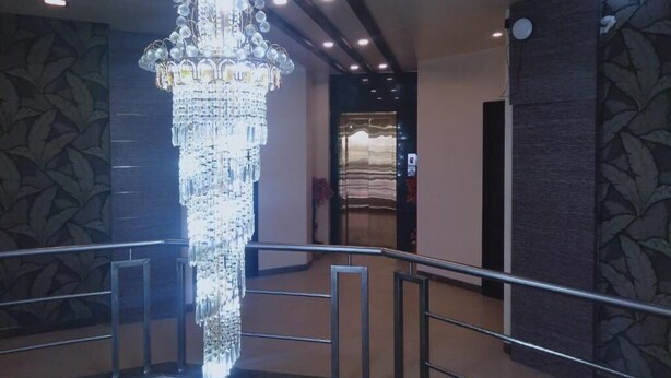 Un magnifique lustre orne un hall d’entrée doté d’un papier peint à motifs et d’un design moderne.