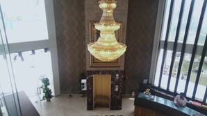 Un hall d’entrée avec un grand lustre, un comptoir d’accueil et un sol en marbre.