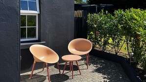 A patio with two chairs and a small table, a window, and a hedge. - 1892 Schoolhouse Killarney - ideal for Ring of Kerry, Dingle & Killarney (Killarney)