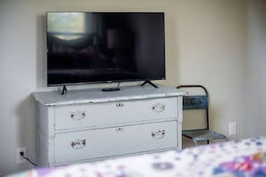 Un aparador blanco con dos cajones y un televisor montado encima.