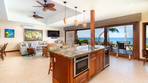 A spacious kitchen with a large island, modern appliances, and a view of the ocean. - Breathtaking Oceanfront Puamana Retreat – 5 Bedrooms, Modern & Spacious (Lahaina)