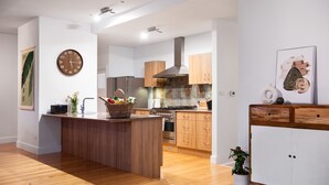 Eine moderne Küche mit Holzschränken, einer zentralen Kochinsel und einer Wanduhr.