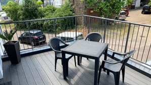 A balcony with a table and chairs, a view of parked cars, and a railing. - Beautiful holiday apartment on the Moselle (Piesport)