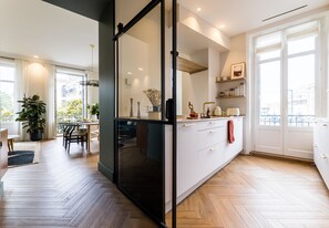 Une cuisine moderne avec une cloison en verre, un plancher en bois et une vue sur la ville grâce à de grandes fenêtres.