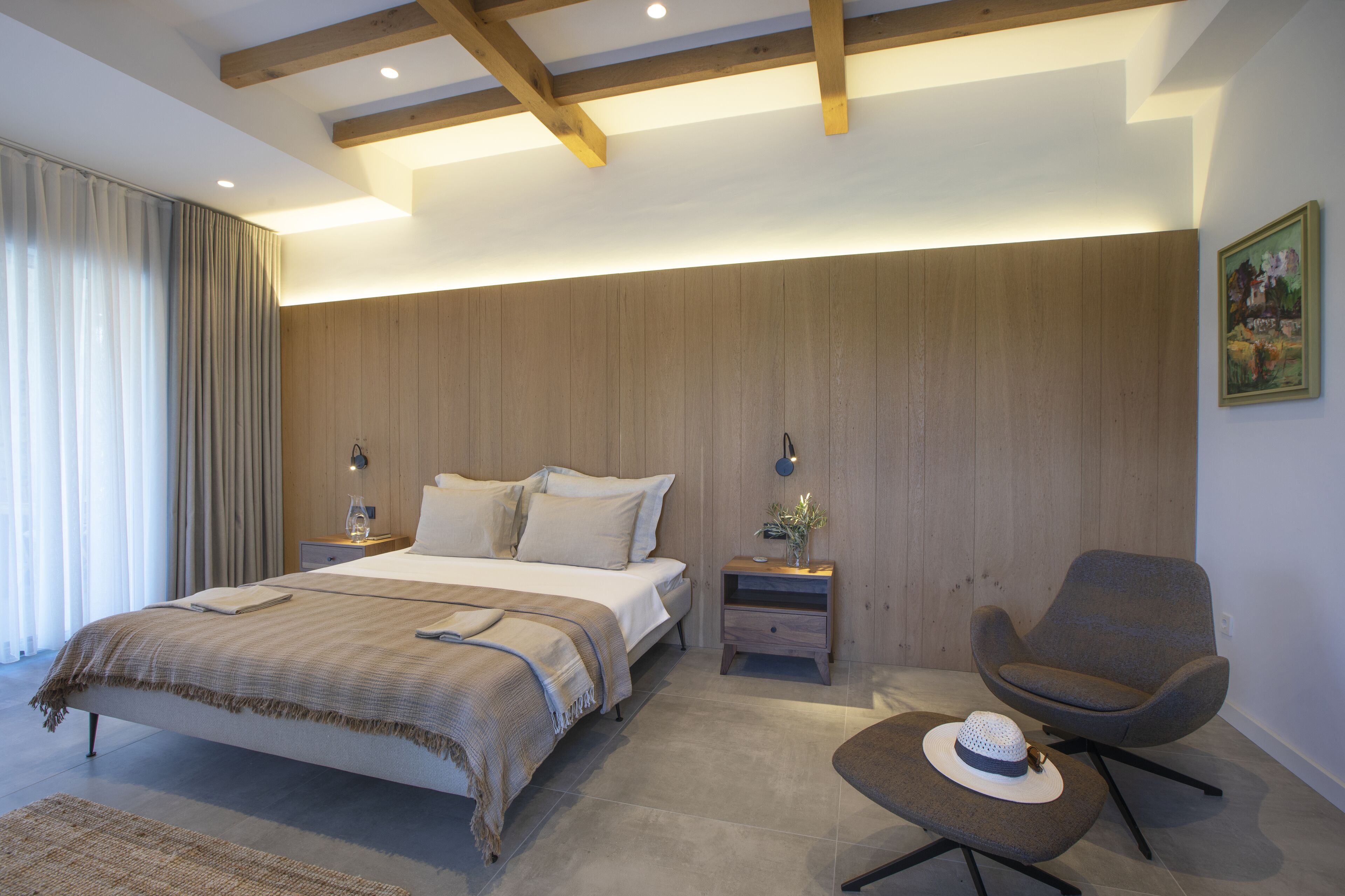 Un dormitorio moderno con una cama grande, mesitas de noche, una silla y un cuadro en la pared.