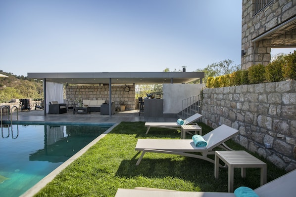 A modern outdoor pool area with lounge chairs and a covered seating area. - Trio'da Kazdaglari (Ayvacik)