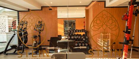 A hotel gym with exercise equipment, wooden walls, and a large mirror.