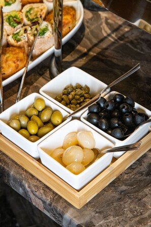 A tray with various food items including olives, capers, and pickled vegetables.
