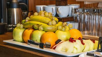 A fruit platter with bananas, apples, oranges, and grapes on a white plate.