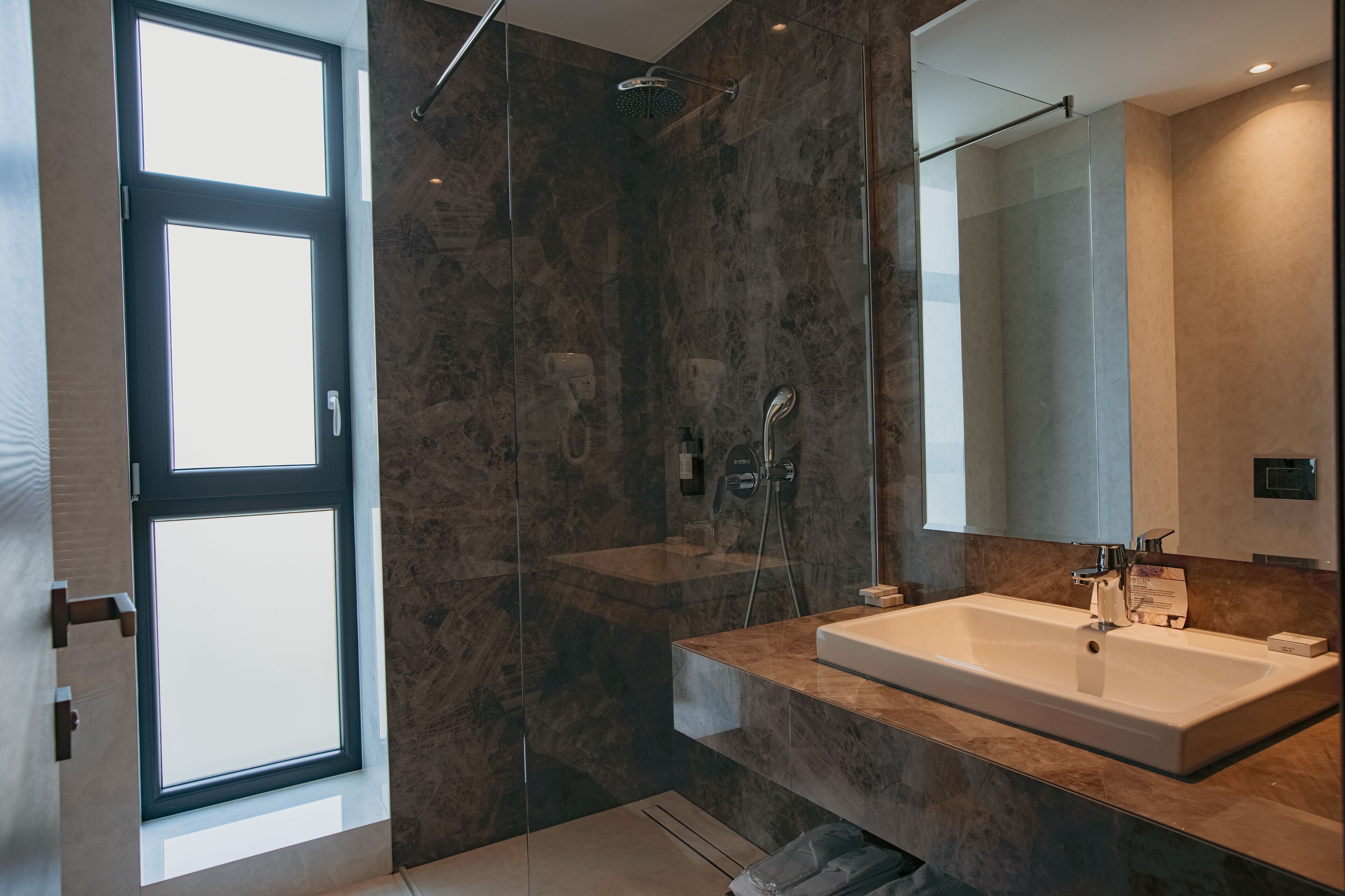 A modern bathroom with a large mirror, a bathtub, and a shower area.