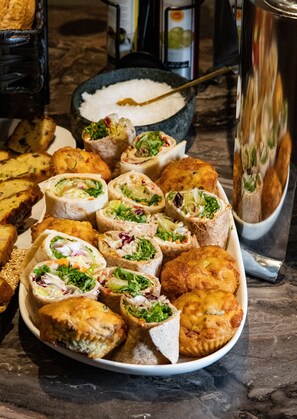 Une variété d’amuse-gueule, notamment des wraps et des plats frits, servis sur une assiette blanche.