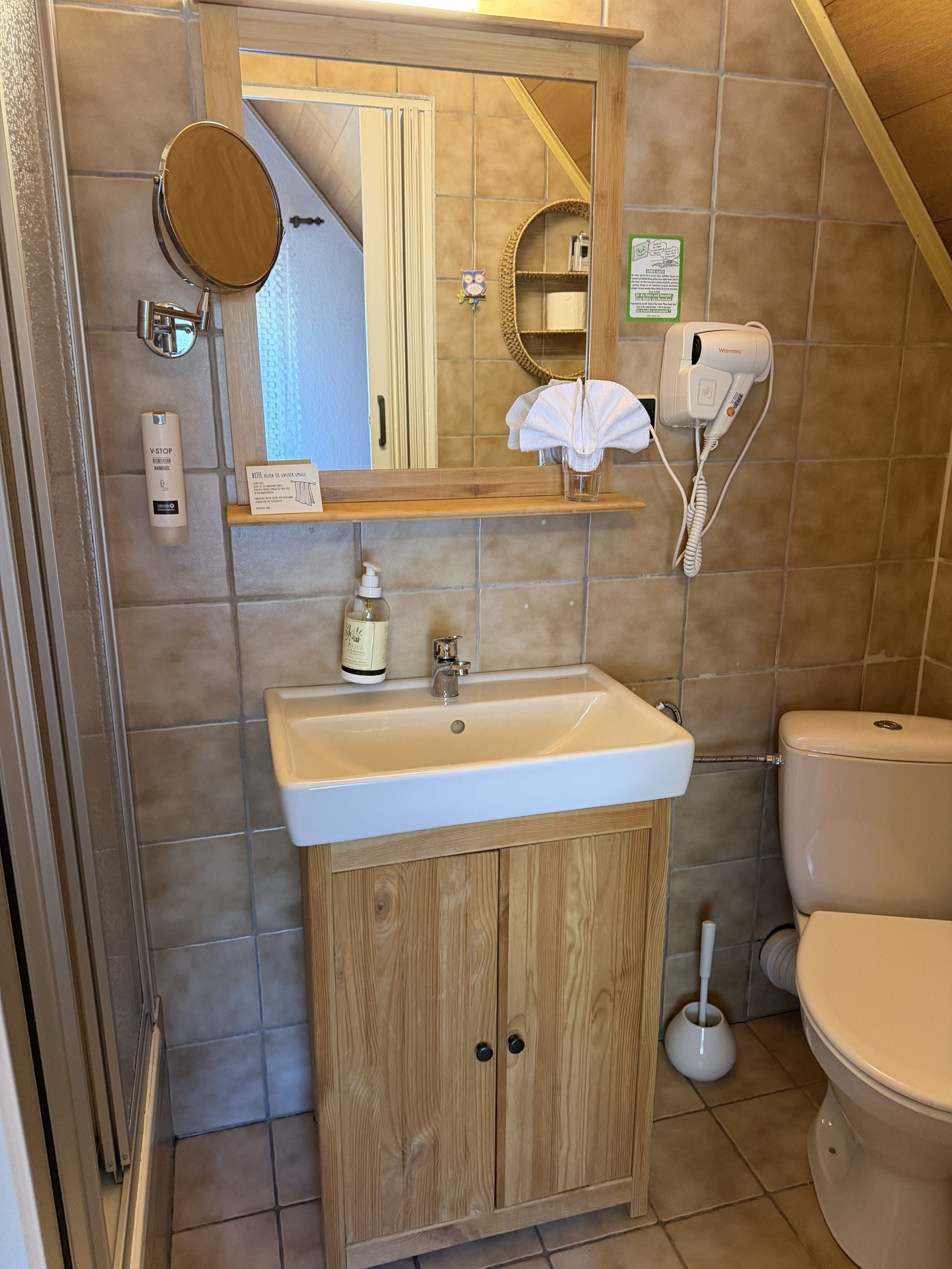 Ein Badezimmer mit Waschtisch aus Holz, einem Waschbecken, einem Spiegel, einem Haartrockner und einer Toilette.