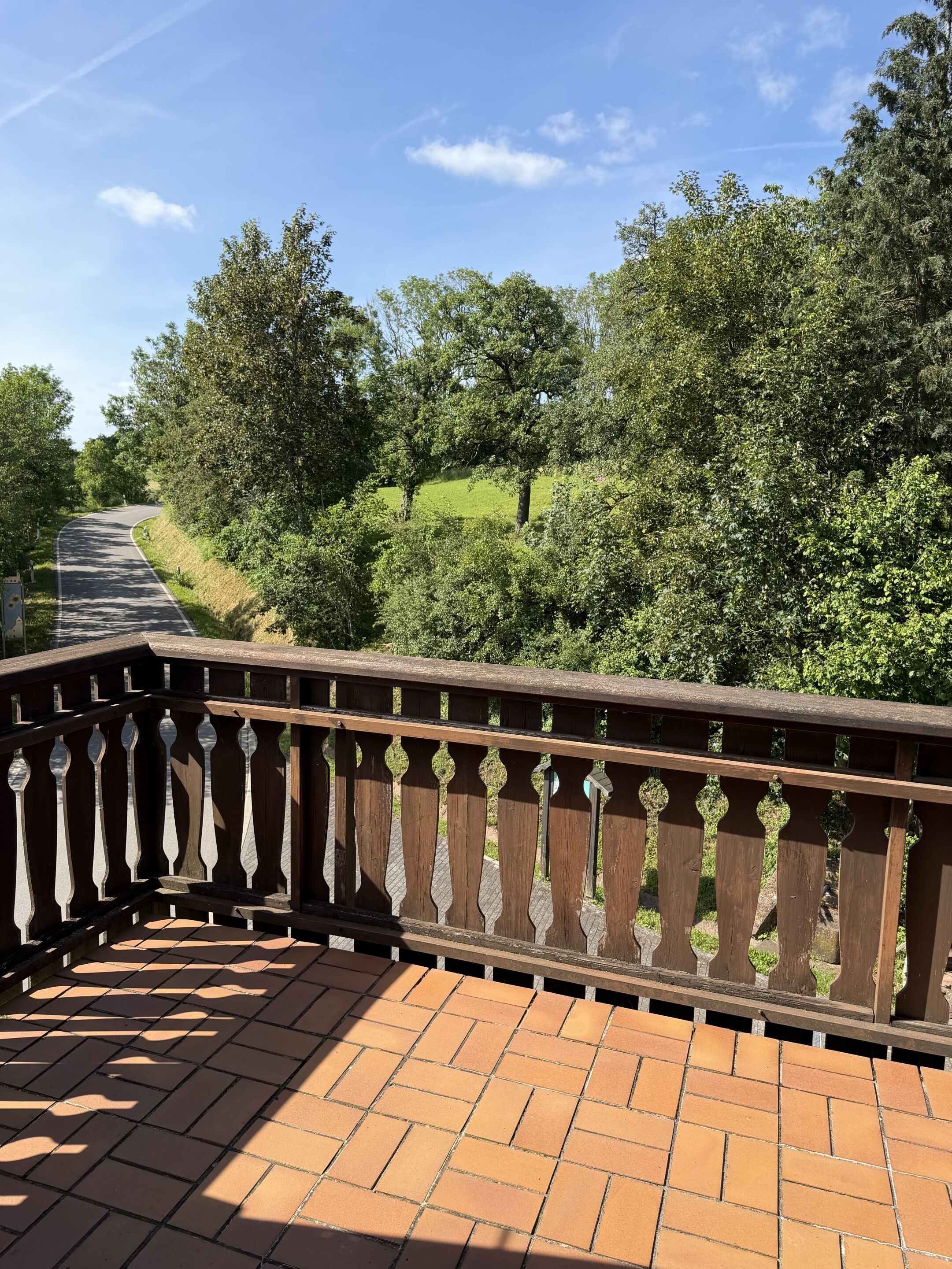 A wooden bridge with a tiled walkway, surrounded by greenery and trees.